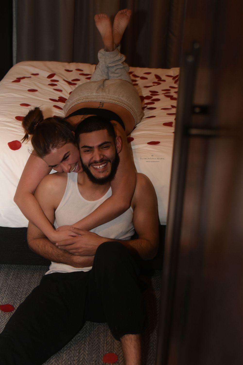 Couple sharing joyful moment on bed with rose petals.