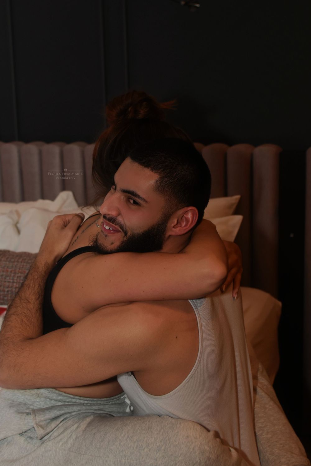 Cozy bedroom scene with couple sharing affectionate moment.