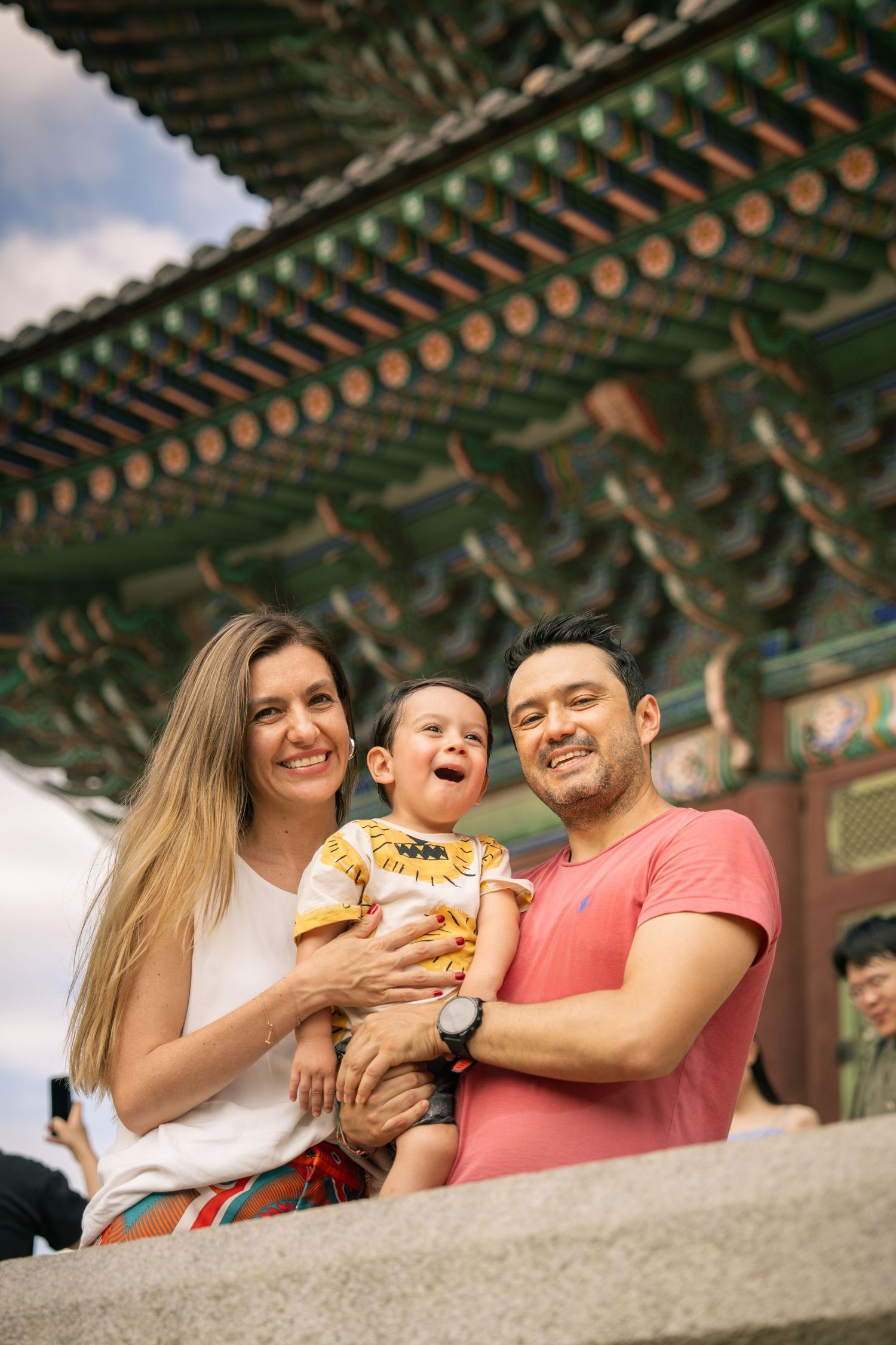 A group enjoys street food together while sitting near traditional Asian architecture with ornate roofing.