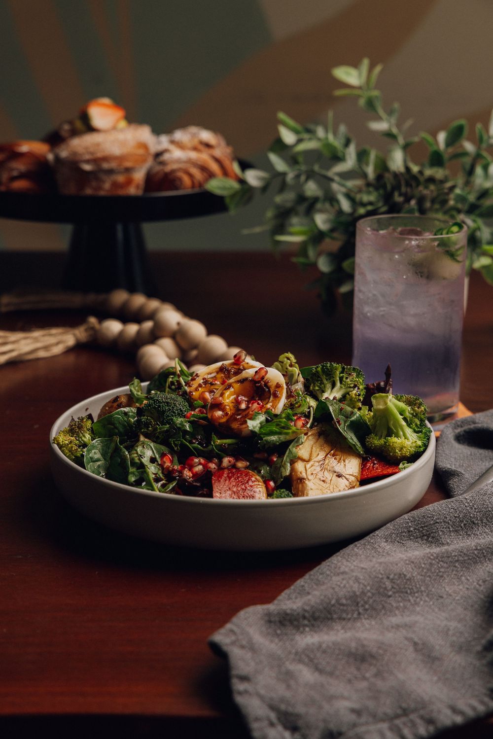 Fresh salads and entrees plated on gray dishes with elegant garnishes in moody lighting.