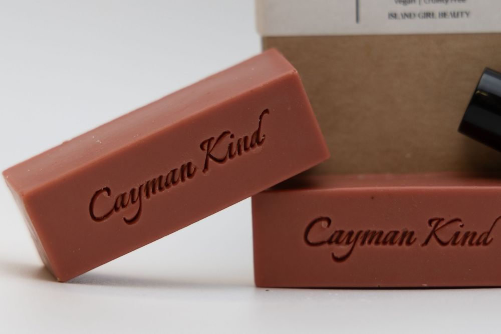 Cayman Kind branded terracotta-colored product boxes arranged in a minimalist composition.