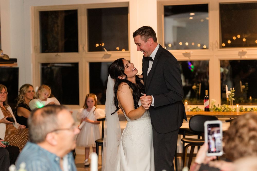 Guests watch a couple share their first dance at an elegant evening wedding reception with twinkling lights.