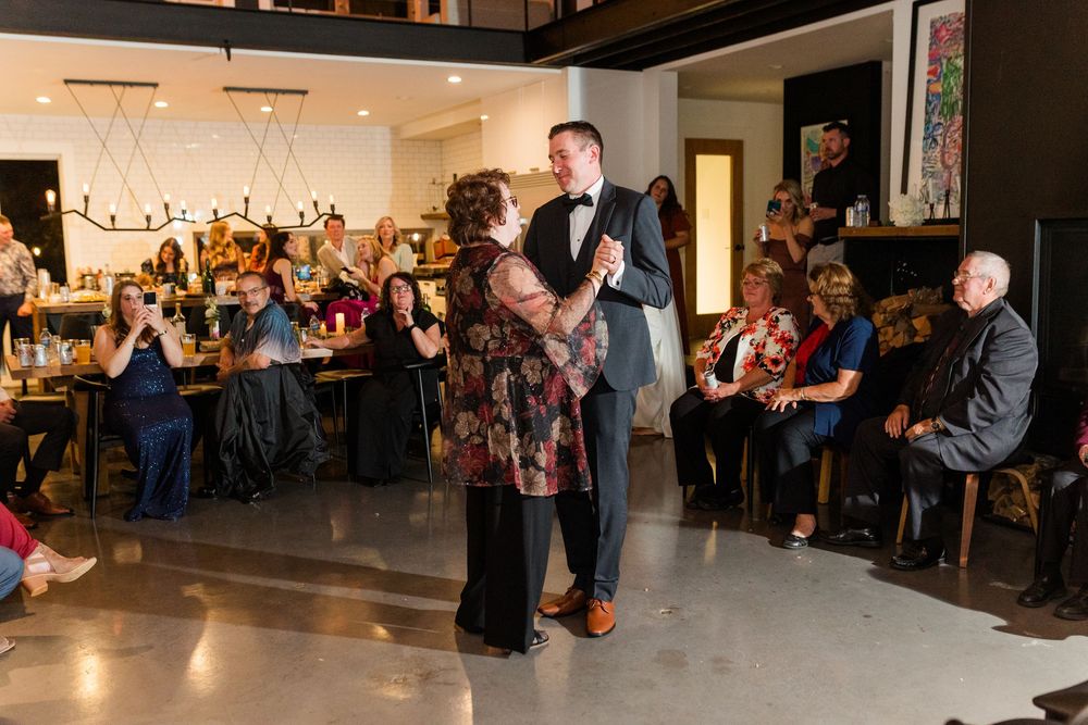 Wedding reception dance floor with guests watching the couple's first dance in a contemporary space.