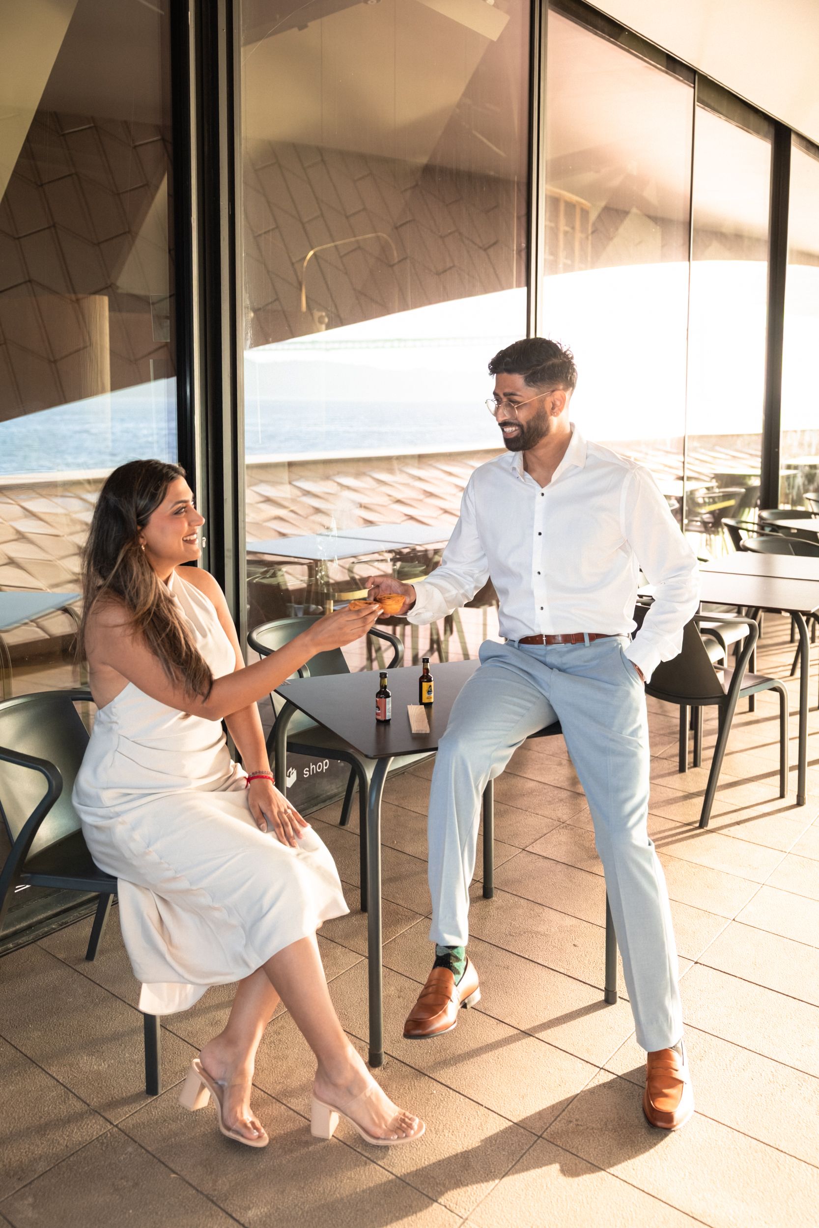 Couple enjoying pastel de nata and Port wine at MAAT Lisbon café after their sunrise engagement session —  by Portugal Wedding Photographer