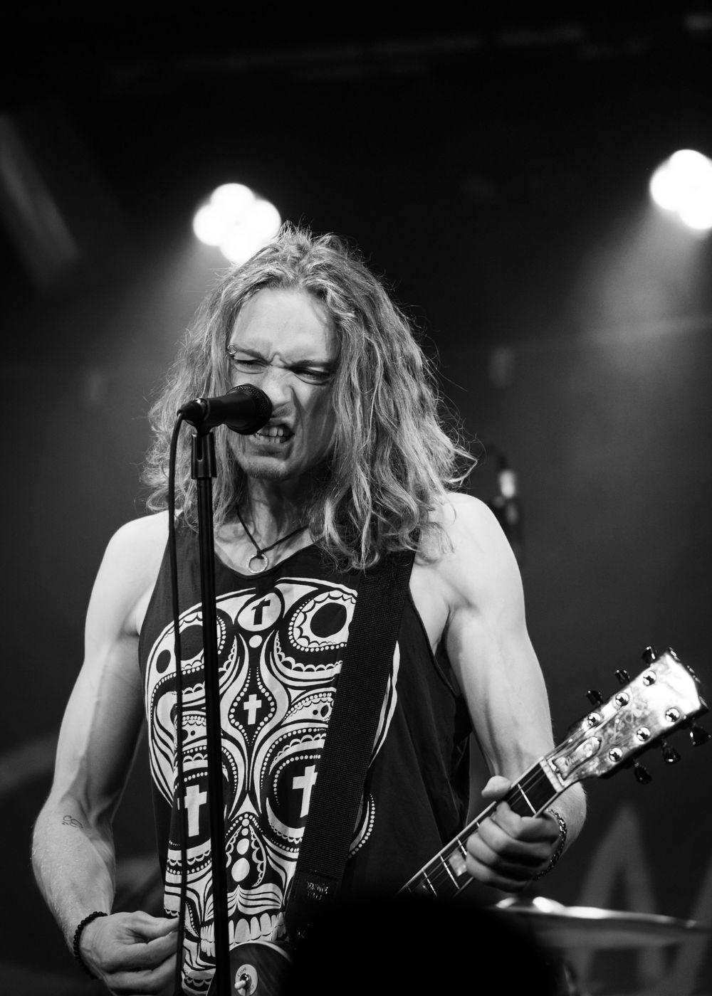Black and white photo series of a heavy metal guitarist performing energetically on stage with long hair.