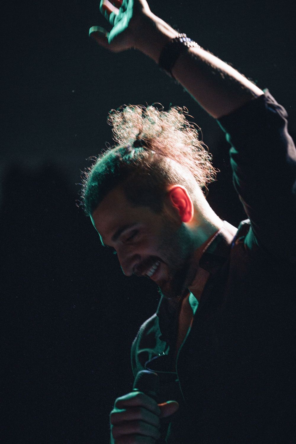 Dramatic side-lit concert photography captures performer in silhouette against dark background.