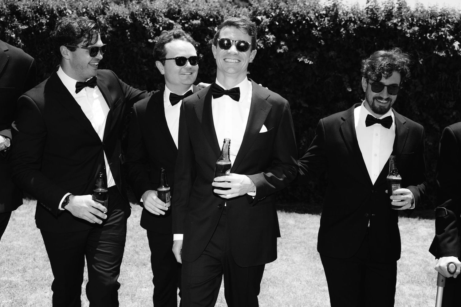 A group of people in formal black attire and sunglasses stand together in a black and white photograph.