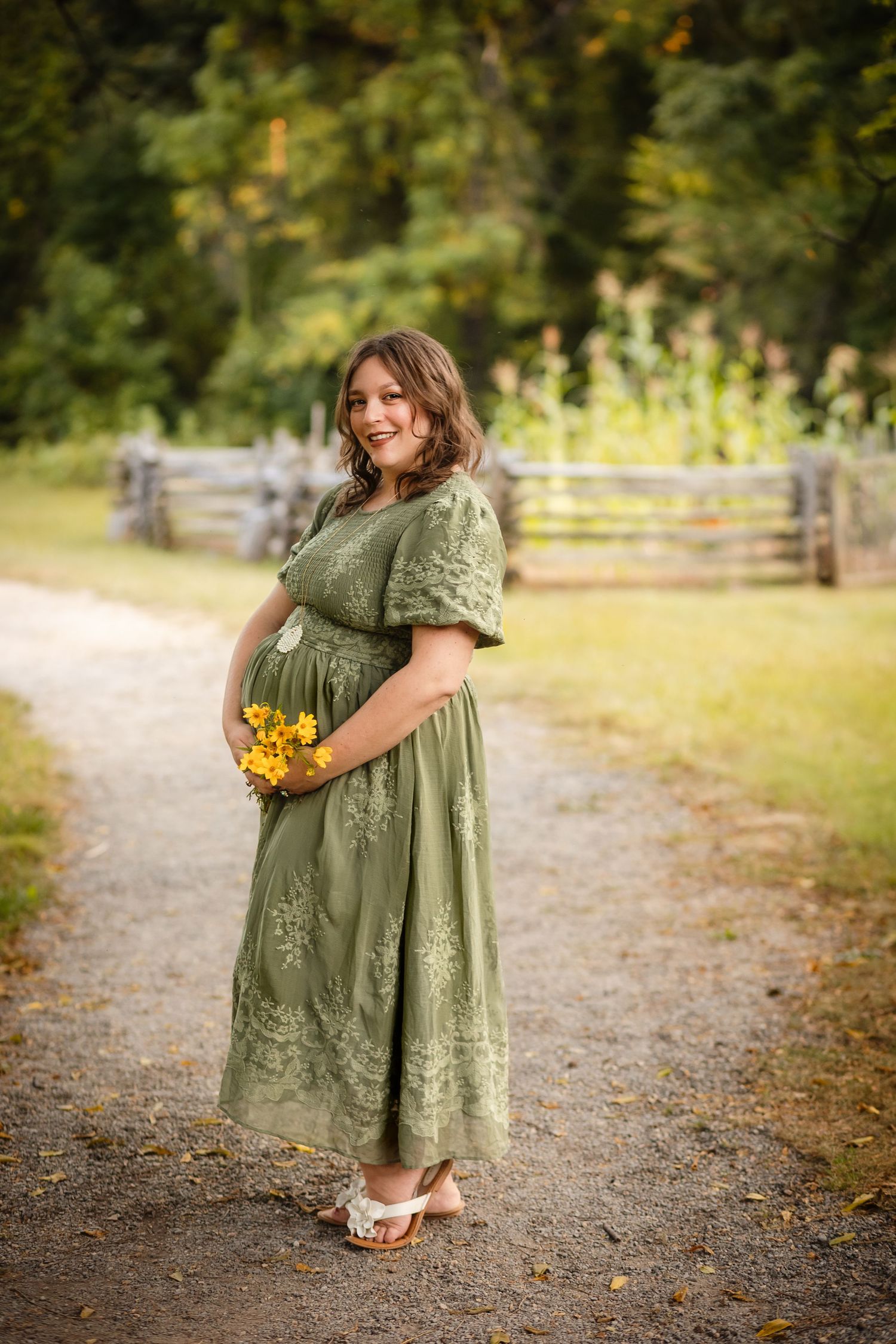 Gorgeous pregnant mother in green adorns her baby bump with yellow Autumn flower near Raven's Roost Overlook, taken by Somerset Portraits.