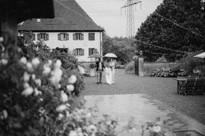 A black and white photograph of a rustic countryside setting with houses and trees.