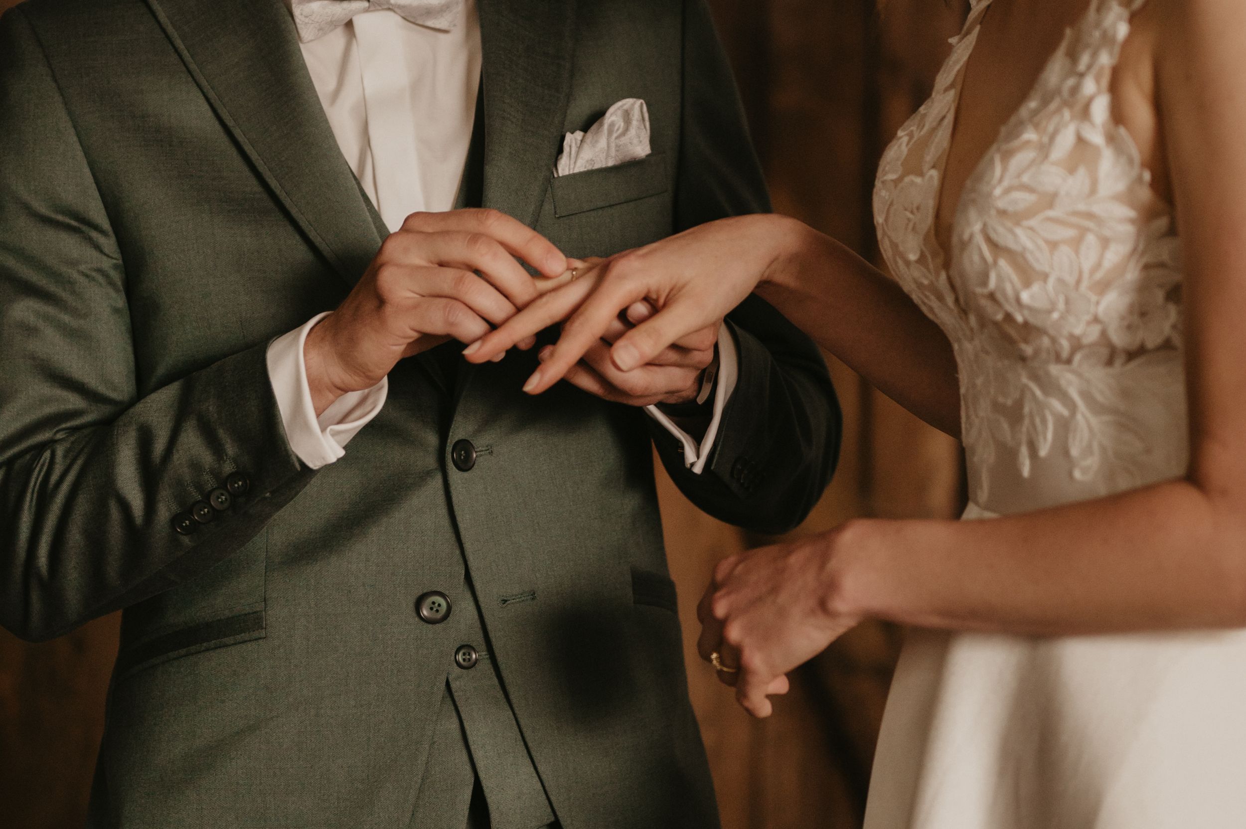Close-up details of hands exchanging rings during a wedding ceremony.