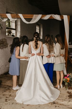 Bridesmaids in pastel dresses standing together with bride in white gown.