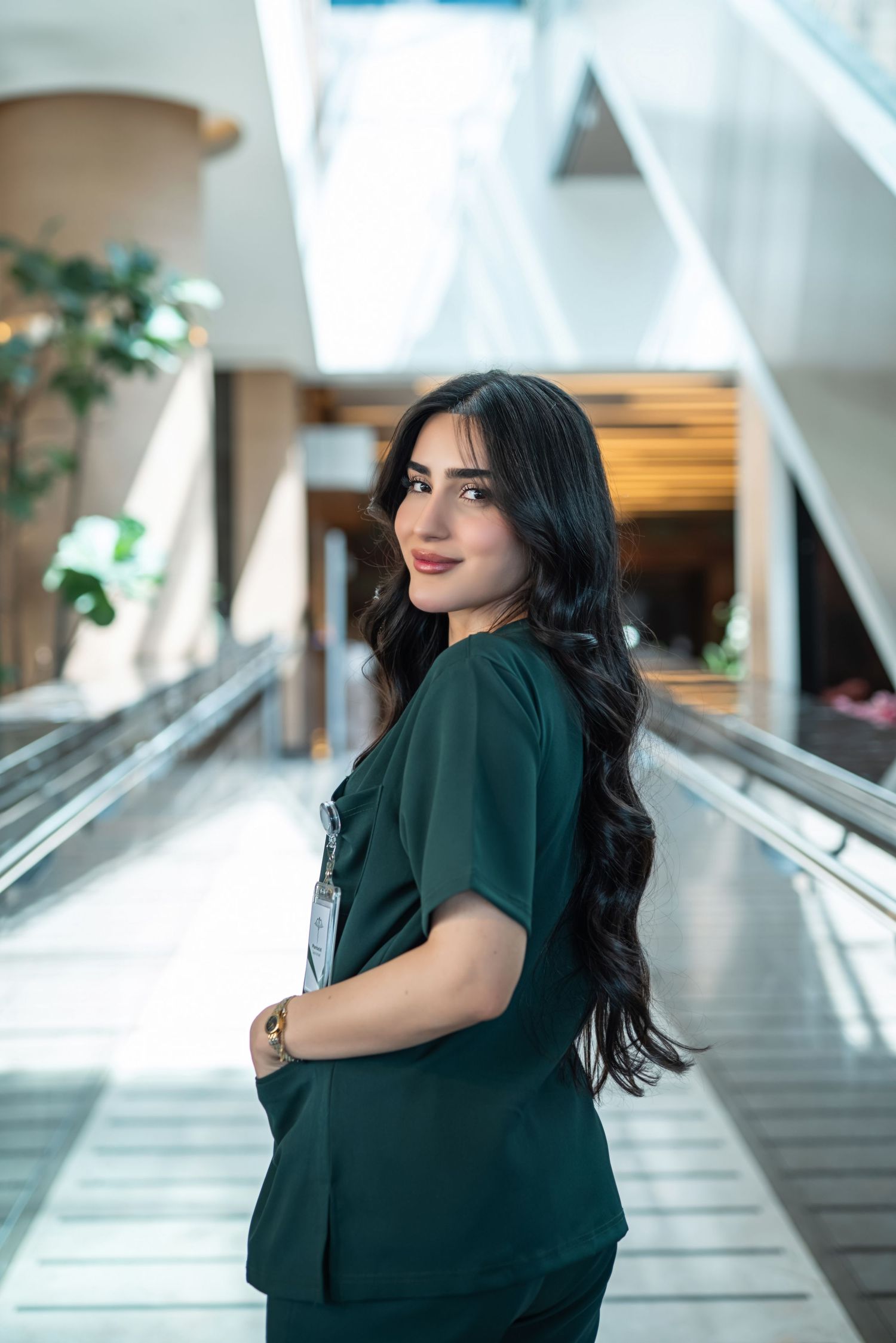 A series of photos showing a woman in a black dress posing in a modern hallway with large windows and natural light.