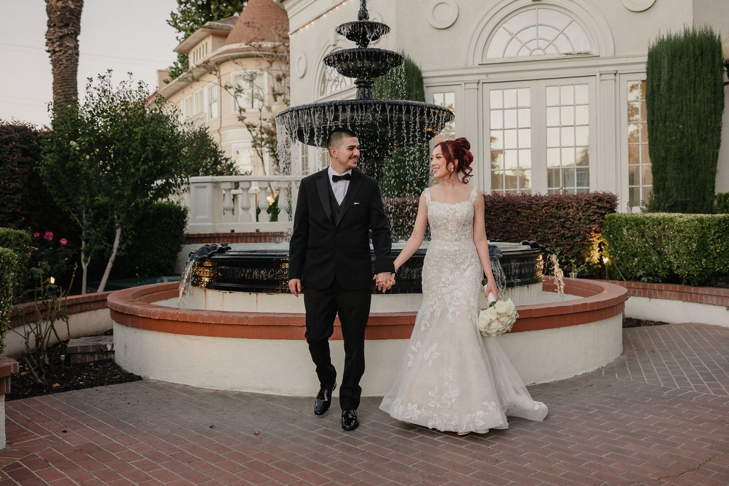 A couple walks together near an elegant fountain outside a grand building with white columns and arched windows for Vizcaya wedding photos