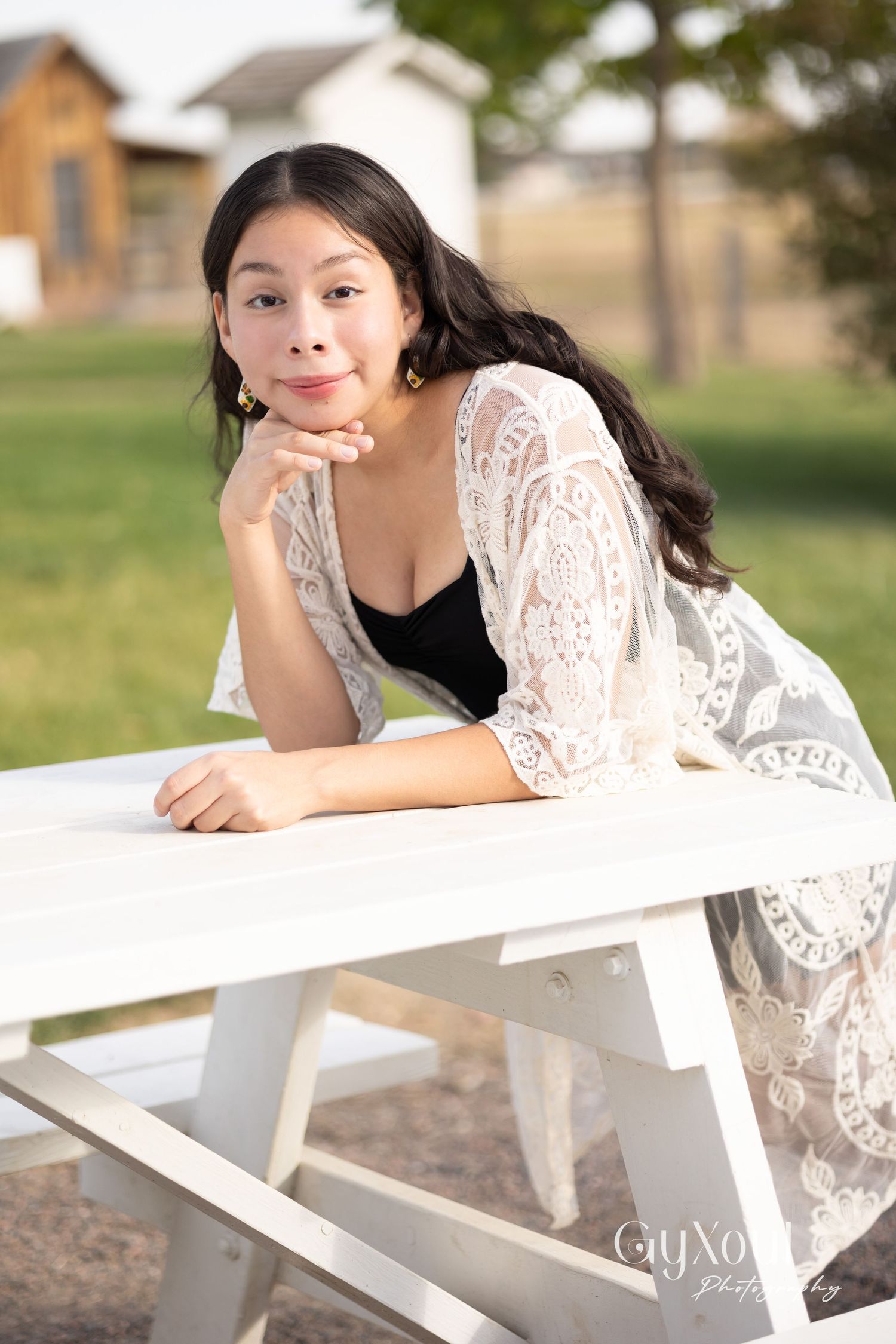 Portrait on white picnic bench with delicate lace overlay and pastoral background.