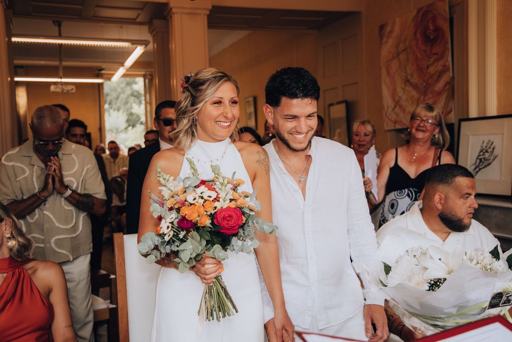 Happy bride and groom walking together holding a vibrant bouquet during their wedding ceremony.