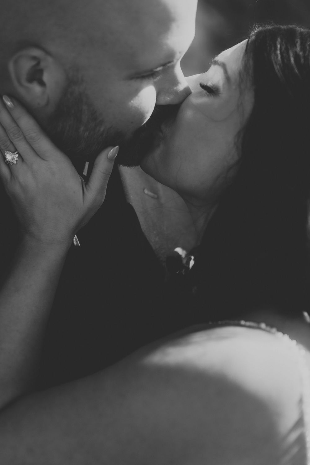 A tender black and white romantic moment captured as a couple shares an intimate kiss.
