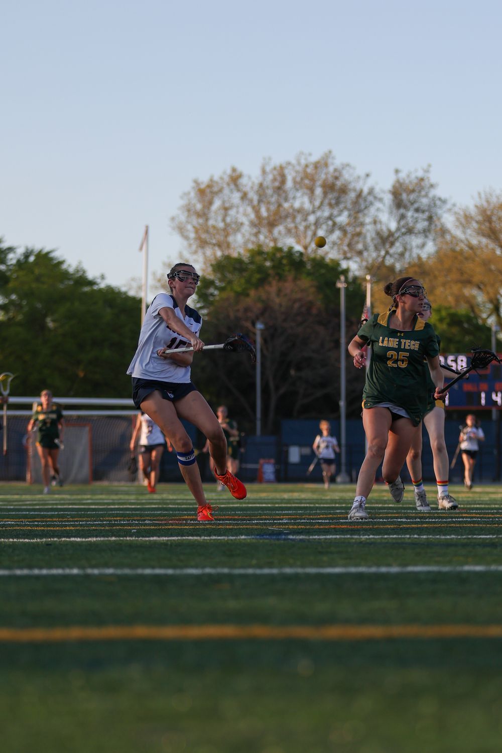 Team members perform synchronized warmup exercises on sports field at dusk.