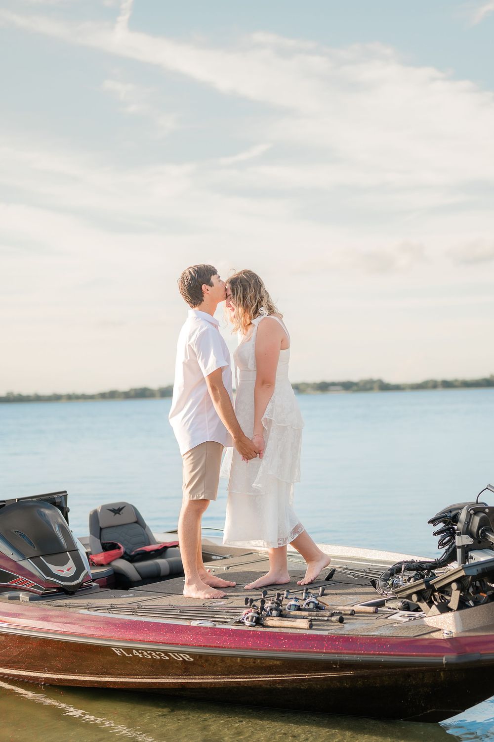 A romantic couple sits together on a boat deck overlooking a serene lake on a sunny afternoon.