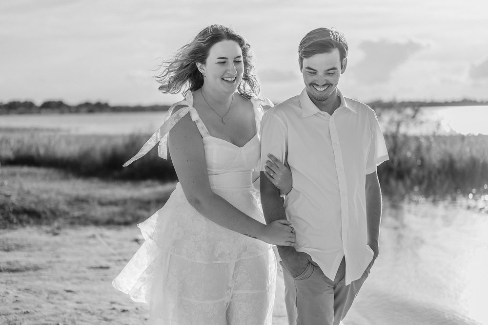 A couple runs playfully through a sun-drenched field during a romantic outdoor photo session.