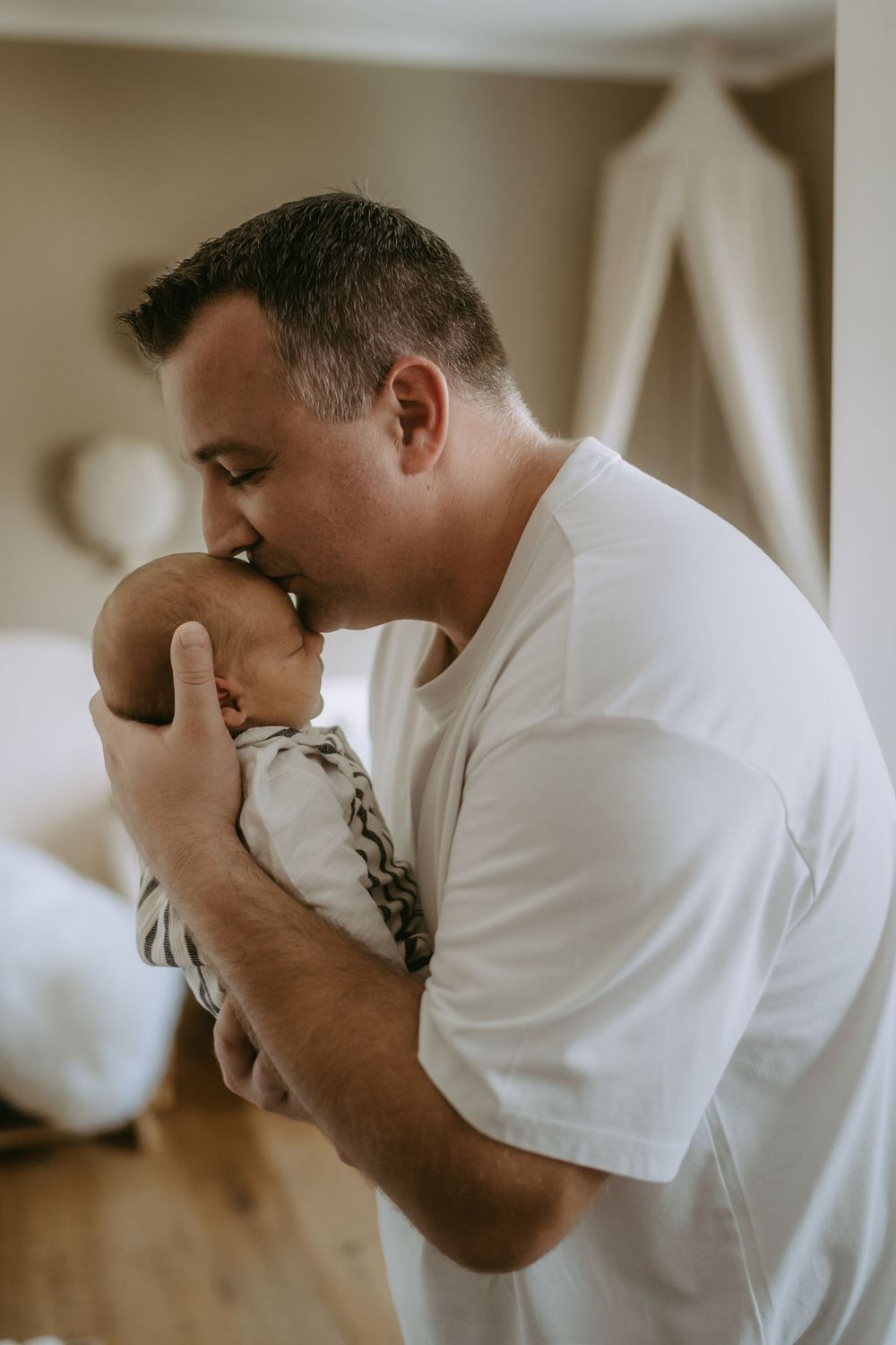 Emotional parenting moment captured in profile against light background.