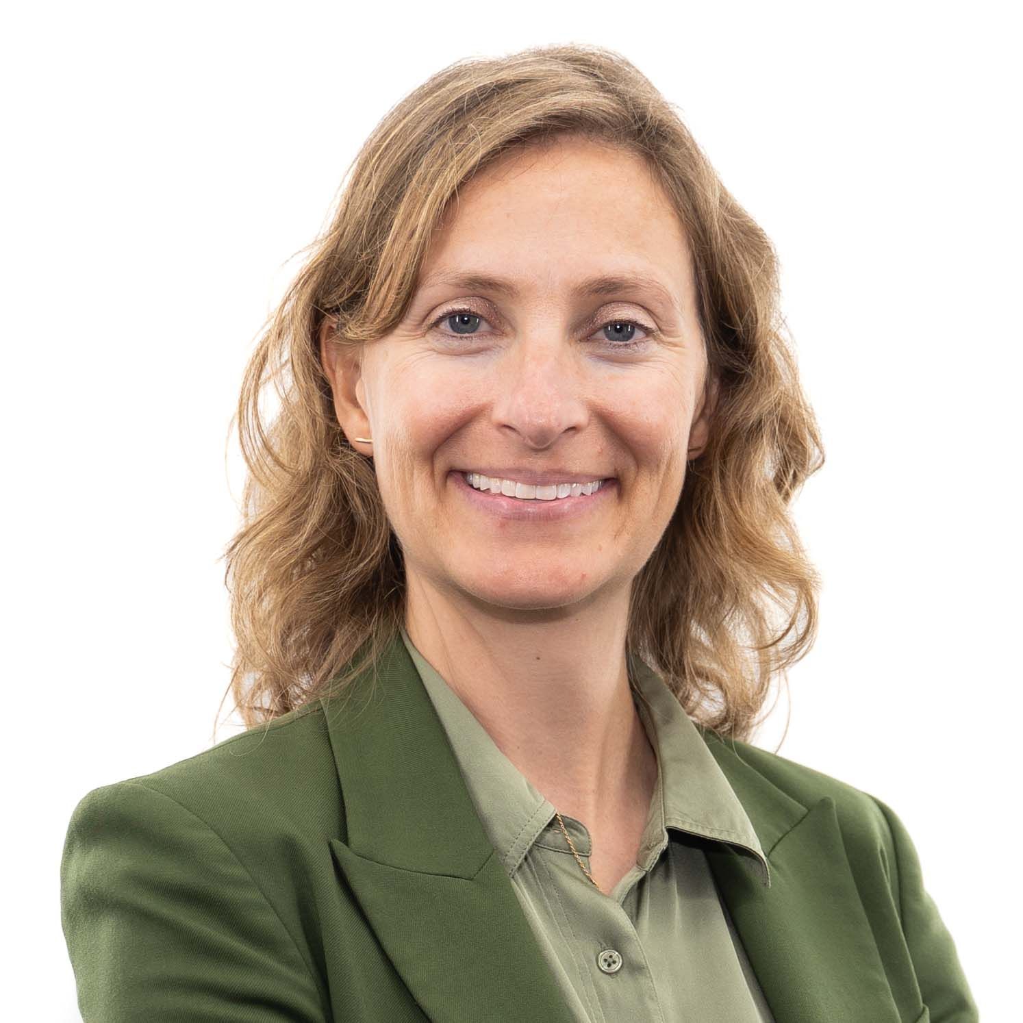 Professional headshot of a person in a green blazer smiling warmly at the camera.