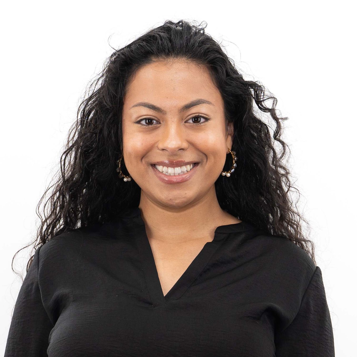Woman with long dark hair wearing a black top smiling confidently at the camera.