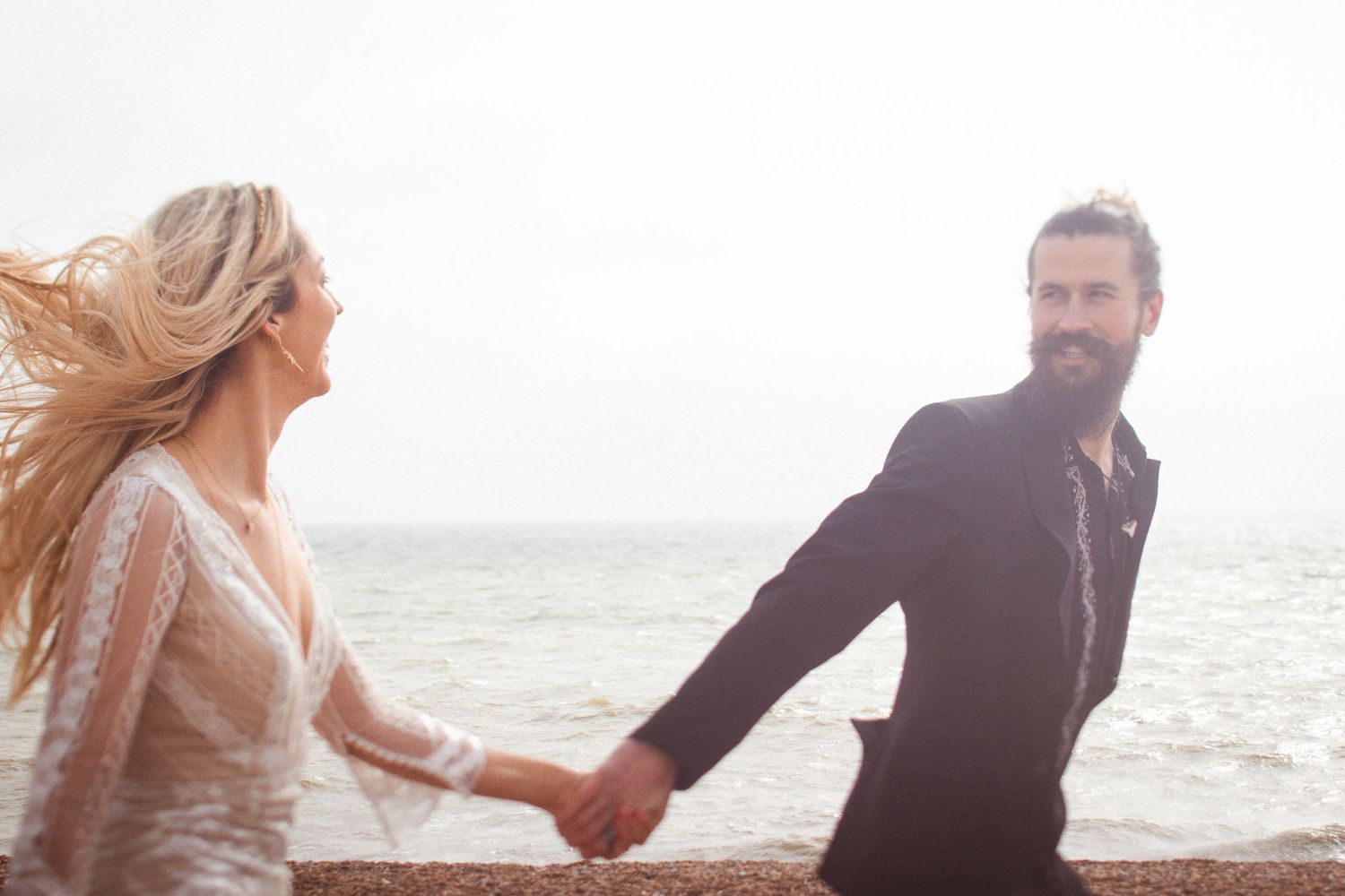 Newlyweds running along the beach after their ceremony at Brighton Town Hall, the light soft and golden — editorial wedding photography