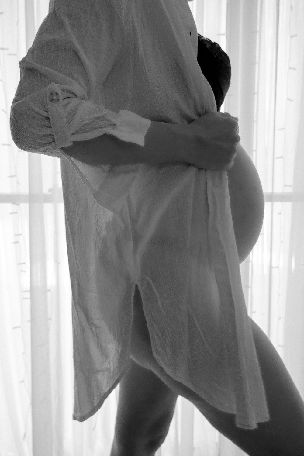Silhouette figure poses in flowing white fabric against backlit window.