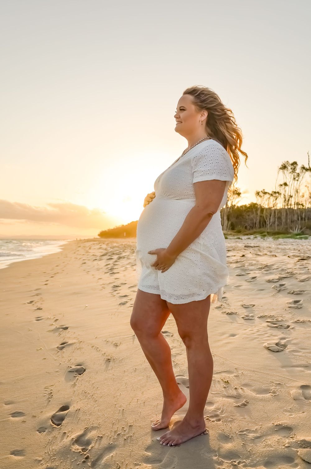 Playful walking poses on sandy beach at sunset with palm trees in background.