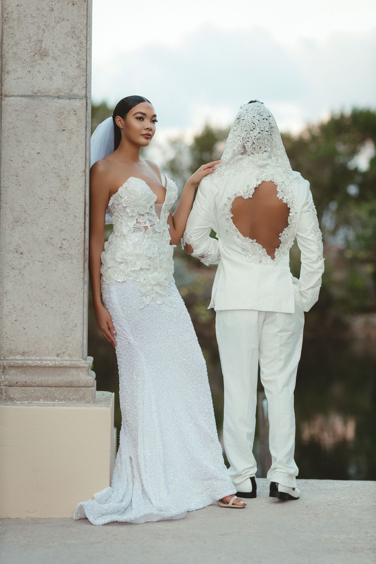 Elegant white wedding dress with lace details photographed outdoors.