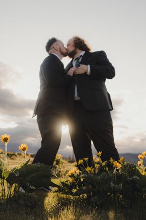 Silhouetted couple sharing romantic moments at sunset among yellow wildflowers in a meadow.