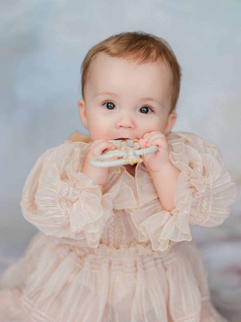 A baby wearing a delicate cream-colored lace dress is shown in a series of sweet portrait poses.