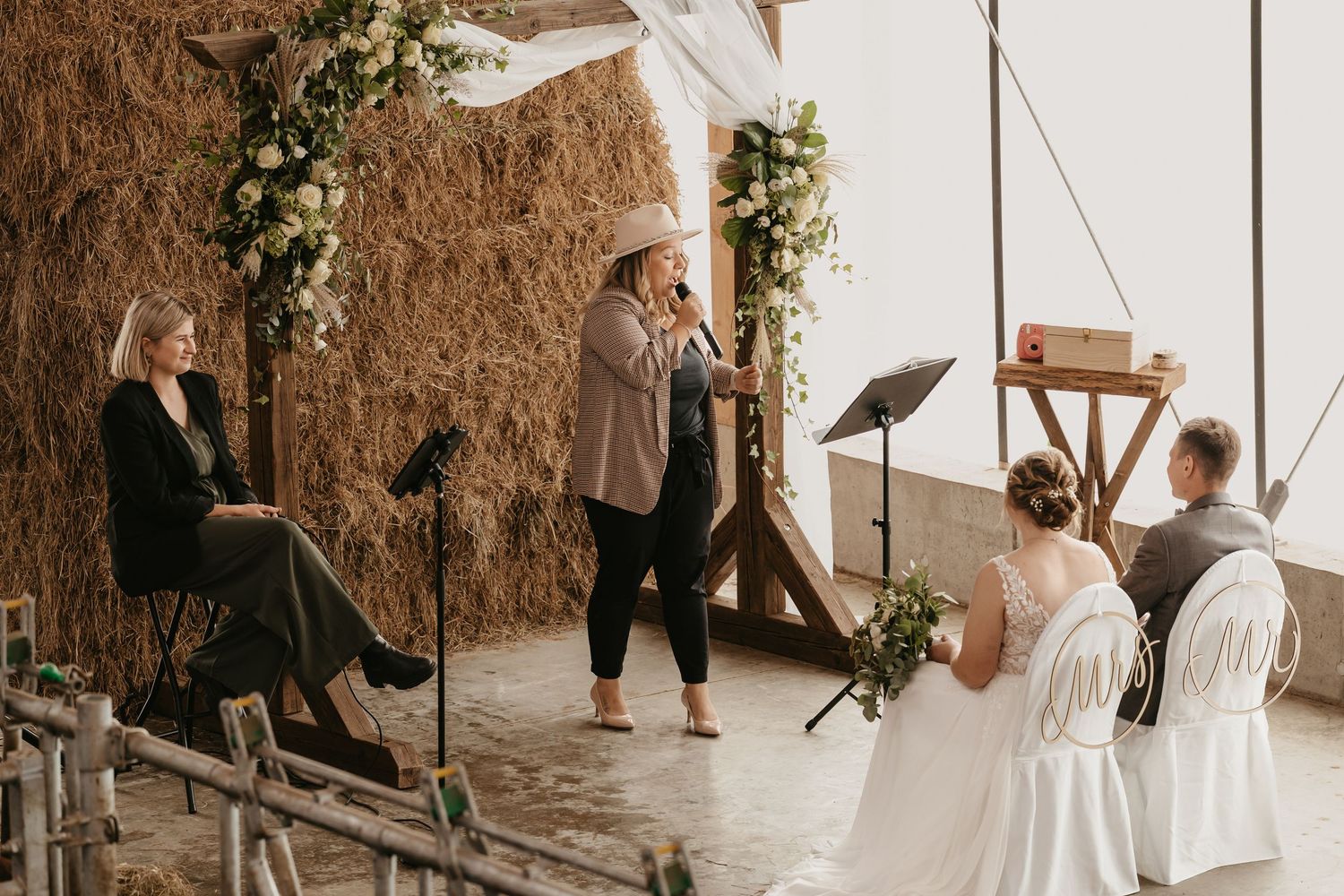 A rustic indoor wedding ceremony with greenery decorations and wooden accents in a cozy intimate setting.