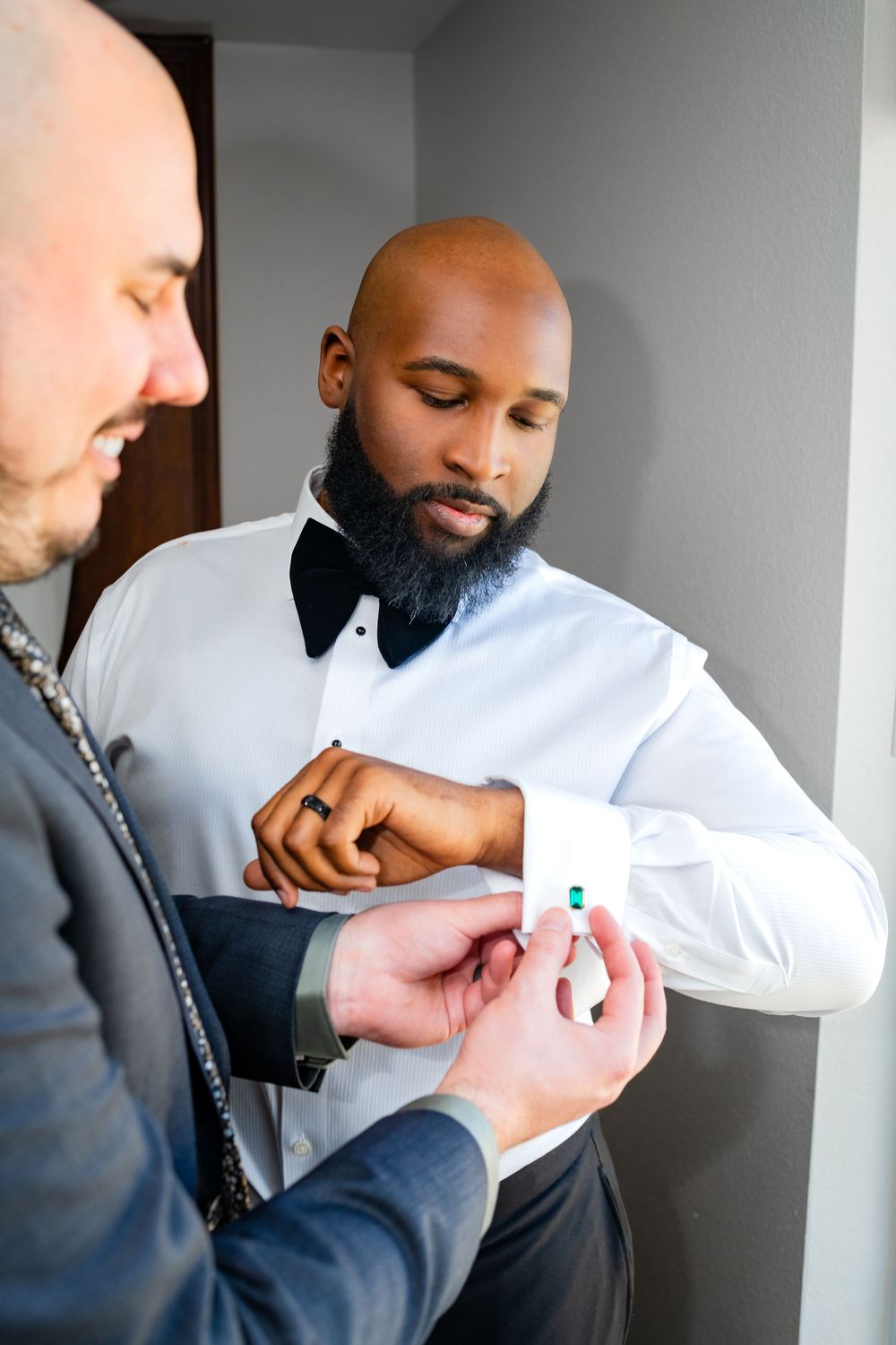 Close-up shots of someone adjusting cufflinks on a white dress shirt sleeve.