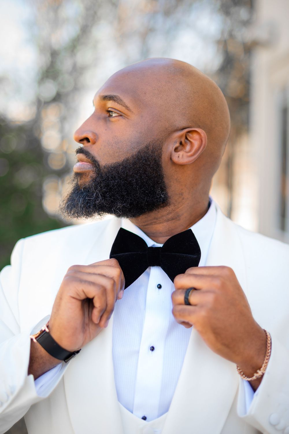 A well-dressed man in a white tuxedo jacket adjusts his black bow tie while looking upward in a series of profile shots.