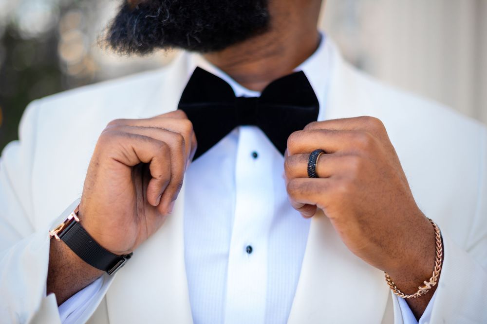 Close-up detail shots of a formal black tuxedo with white dress shirt and accessories being adjusted.