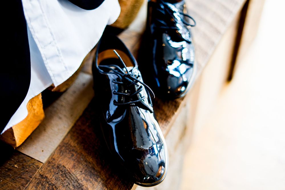 Detail shot of formal black dress shoes on wooden surface.
