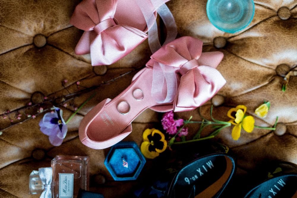 Wedding details flatlay with pink ribbons and turquoise accents on vintage wooden surface.