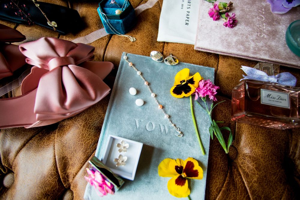 Wedding details including vows, flowers, and pastel accessories on textured surface.