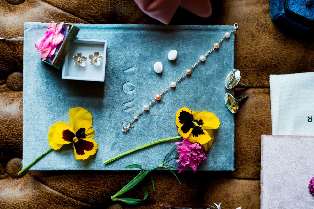 Jewelry and yellow pansies arranged on blue surface with decorative styling elements.