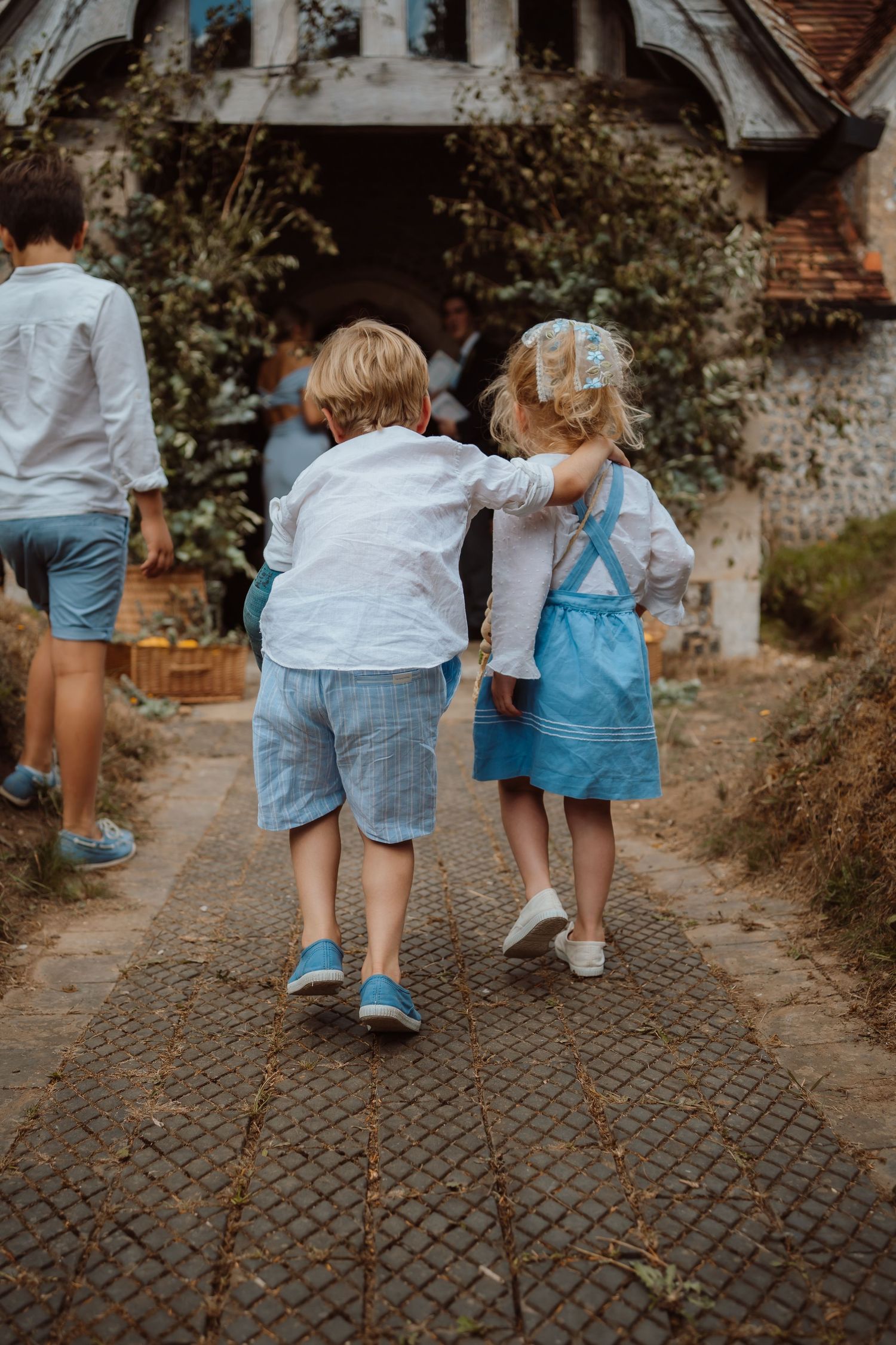 People walking together on a cobblestone path wearing coordinated blue and white outfits in a casual outdoor setting.
