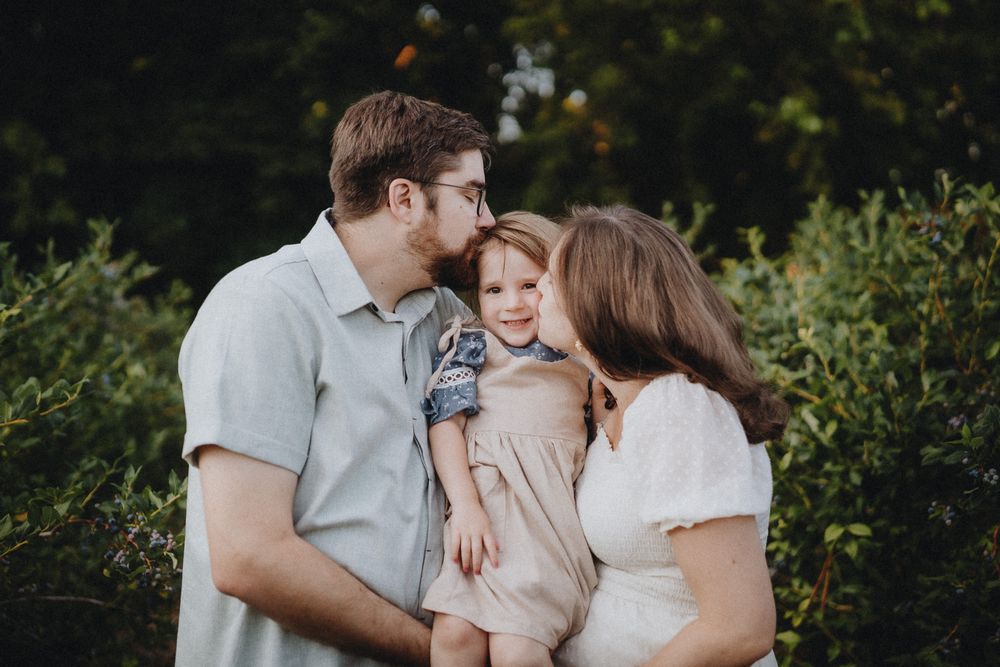 Loving family moment captured in outdoor garden setting.