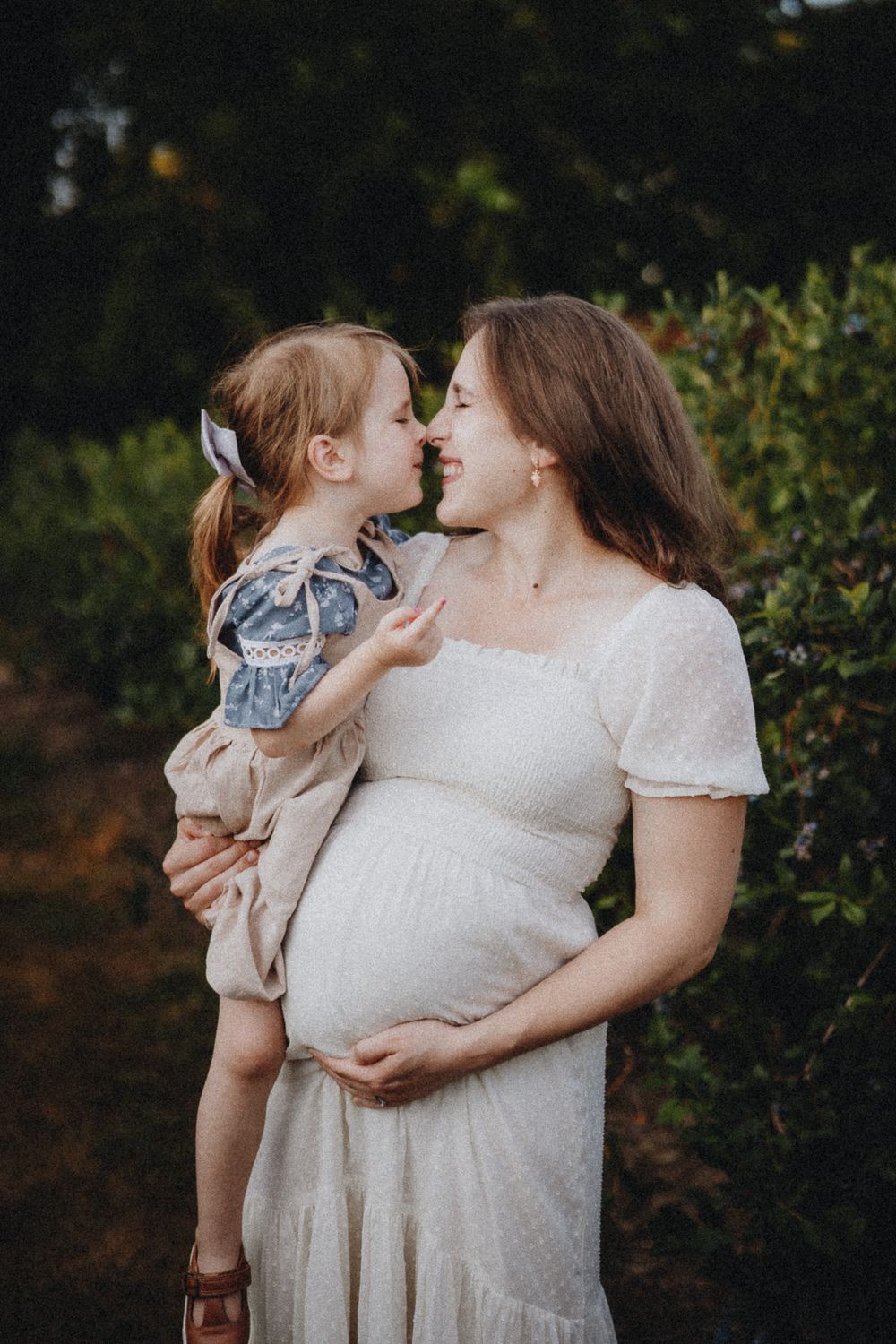 Intimate family portrait showing tender moment in garden setting.