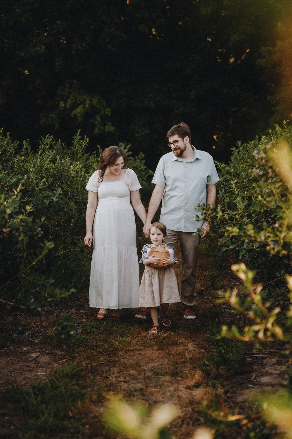 Family walking together through garden path at golden hour.