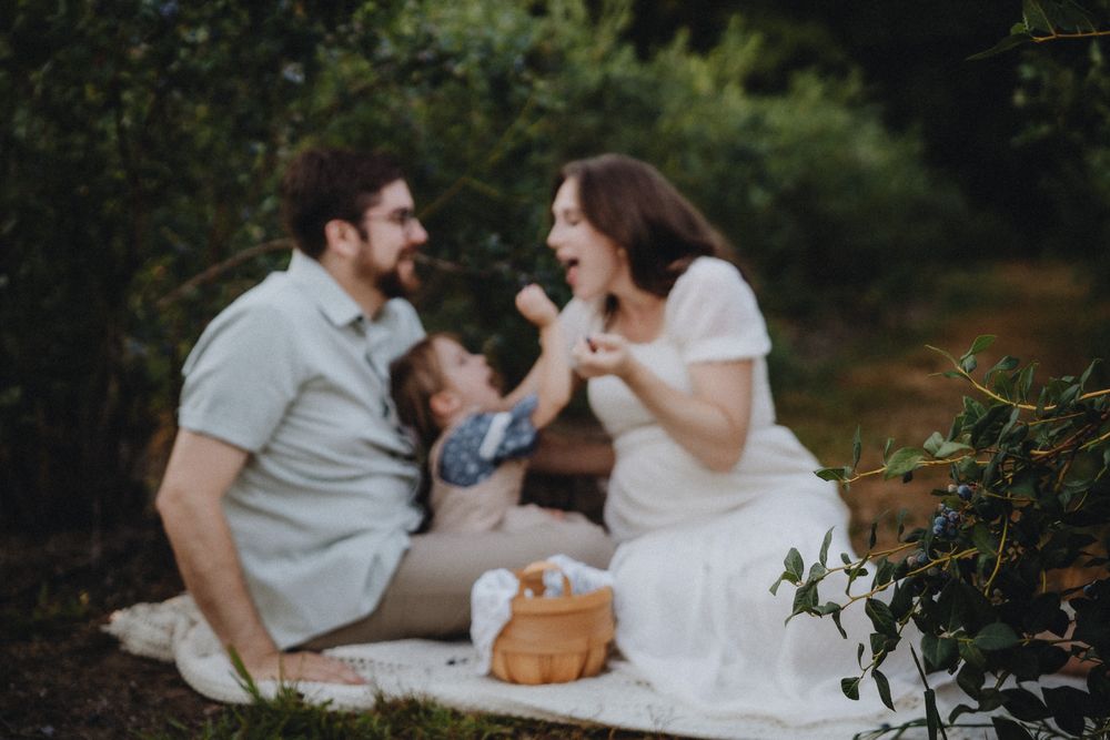 A family enjoys quality time together during an outdoor photoshoot on a white blanket.