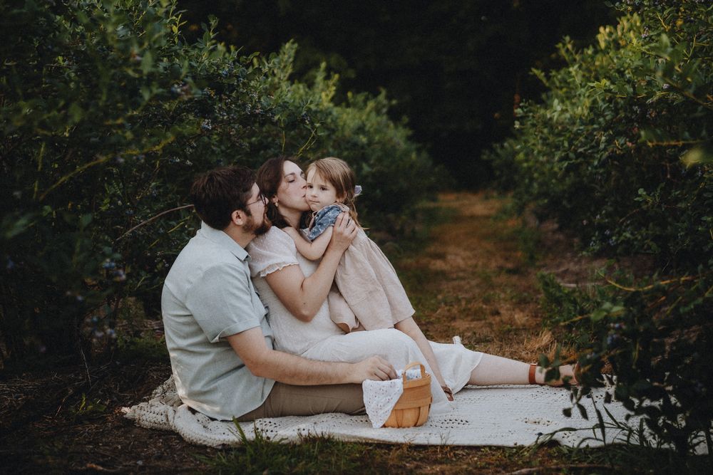 A sweet family scene unfolds during a rustic outdoor photography session.