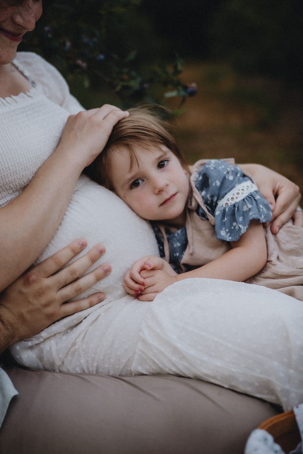 A gentle moment of rest captured on a soft white blanket during an outdoor photo session.