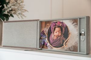 Wall-mounted display case showcasing professional newborn and family photography.