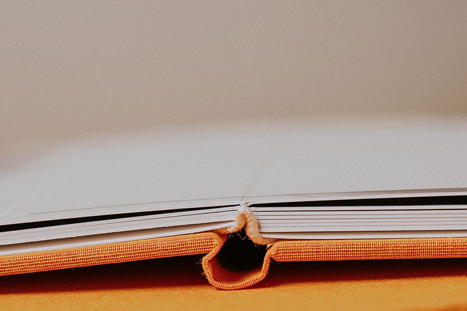 Close-up macro shot of an open book spine showing orange binding and pages.