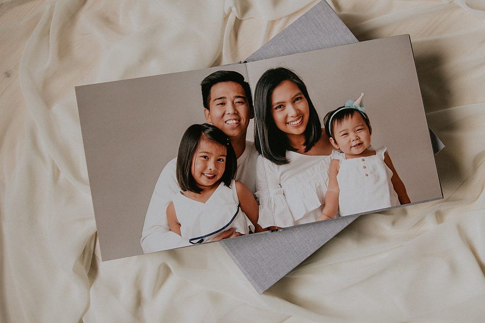 Photo album pages showing family memories laid out on white fabric background.